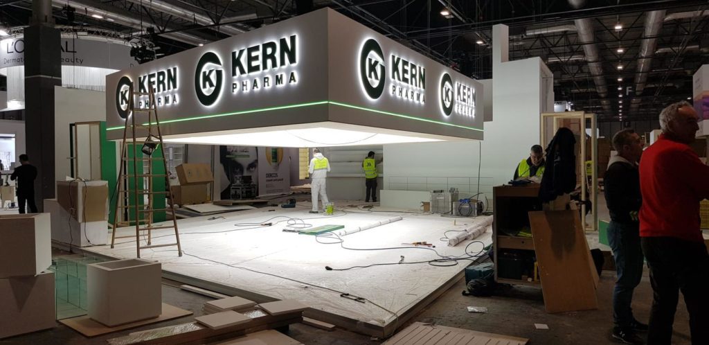 Detalle de la estructura superior de aluminio retroiluminada del stand, que resalta el logotipo de Kern Pharma y garantiza una visibilidad óptima.