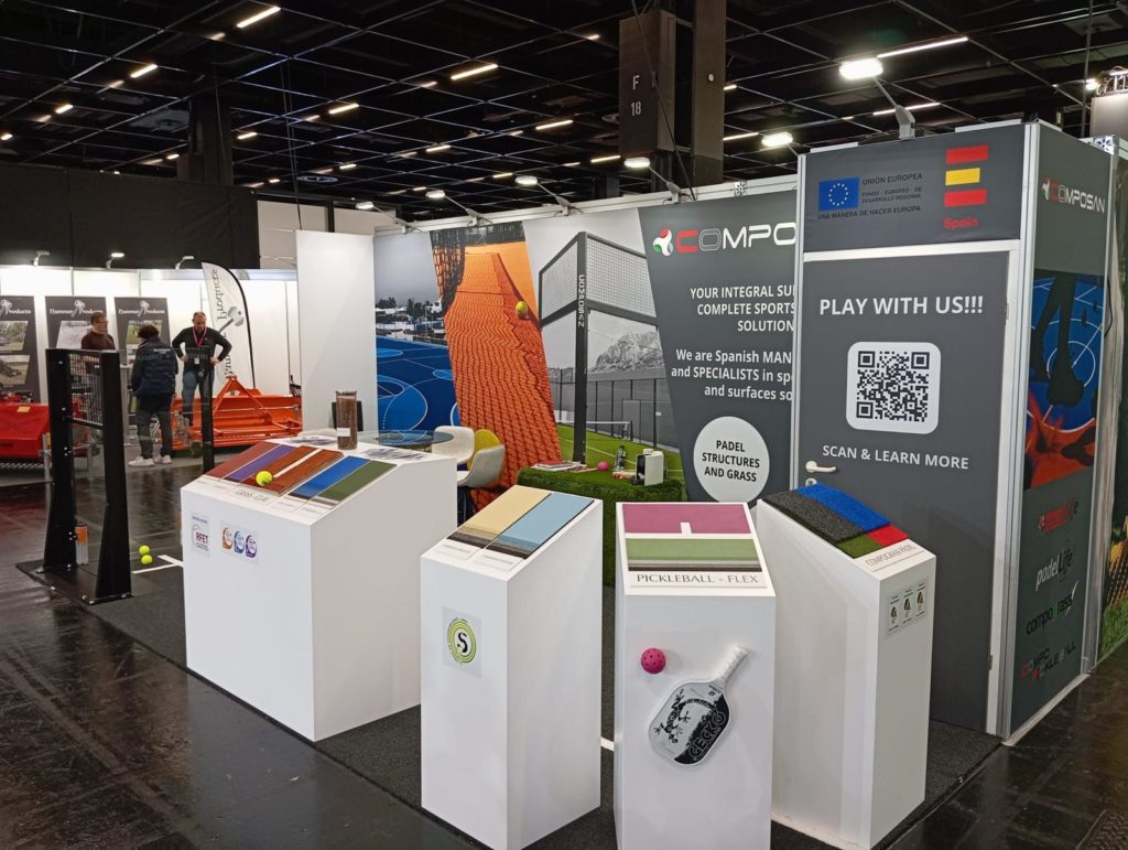 Vista general del stand Composan en feria, con fondo gráfico, mobiliario técnico y zona de reuniones.