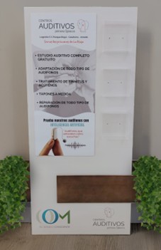 Expositor PLV instalado en tienda auditiva, con cartelería informativa, estantes y compartimentos acrílicos.