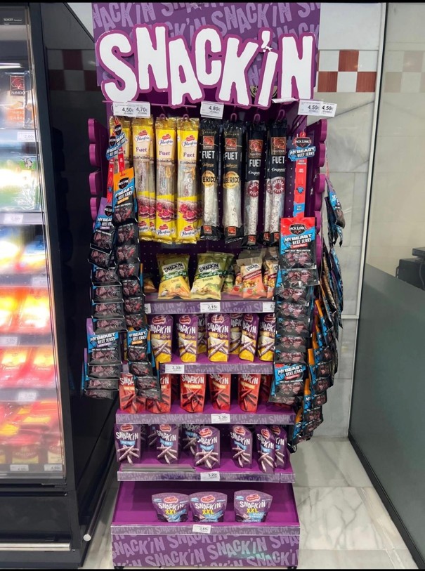 Expositor multiproducto Snack’in con diferentes niveles y ganchos para snacks.